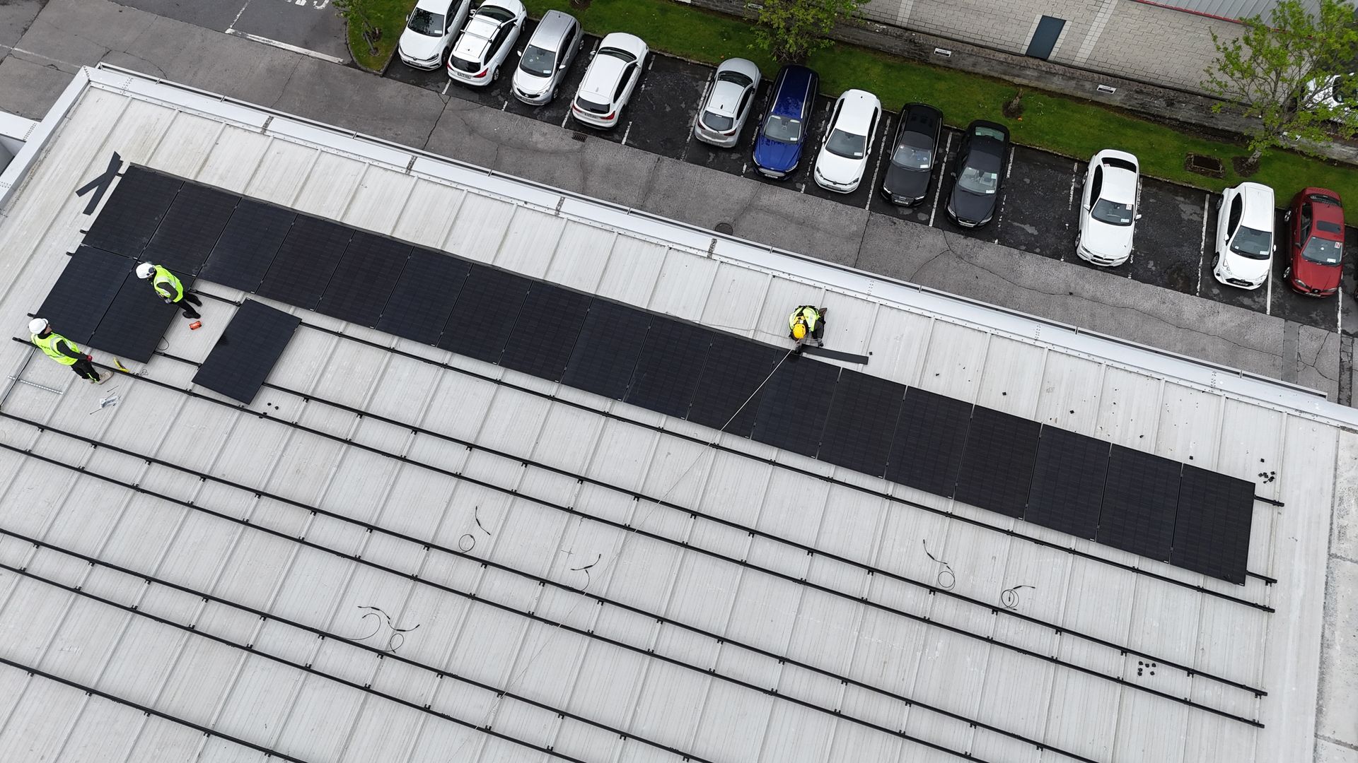 Image of Solar Panel installers installing solar panels on a roof with safety harnessing